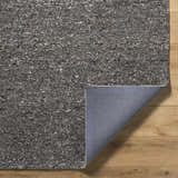 Close-up of the hand-tufted Sevan Black Wool Area Rug showing its jet black, medium gray, and taupe textured design. Fold
