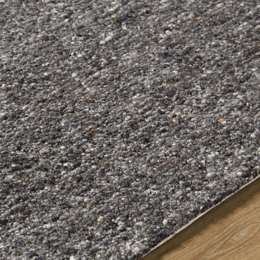 Close-up of the hand-tufted Sevan Black Wool Area Rug showing its texture and blend of jet black, gray, and taupe tones. Texture
