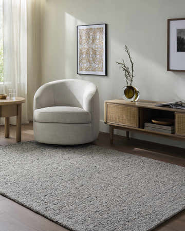 Living room scene with a gray Sevan Wool Area Rug, beige chair, wood media console, and neutral decor. Roomscene-Rectangle