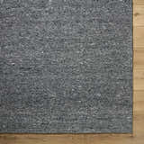 Close-up of the charcoal gray Sevan Wool Area Rug showing its textured, hand-tufted weave and neutral color palette. Corner