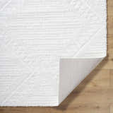 Close-up of the off-white Edsel shag rug showing its plush texture and backing on a wood floor. Fold