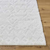 Close-up of the plush white Hoshi Area Rug showing its shag texture and subtle geometric pattern on wood floor. Front