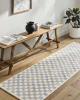 Entryway with a Halen Gray Checkered Area Rug, wood bench, books, vases, and potted plant. Roomscene-Runner