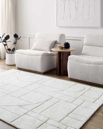 Living room scene with beige Fusao Area Rug, two armchairs, wood side table, and neutral decor. Roomscene-Rectangle