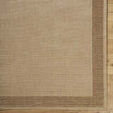Close-up of the Inigo Flatweave Faux Jute Rug. Beige rug with a dark brown border on a wood floor. Corner