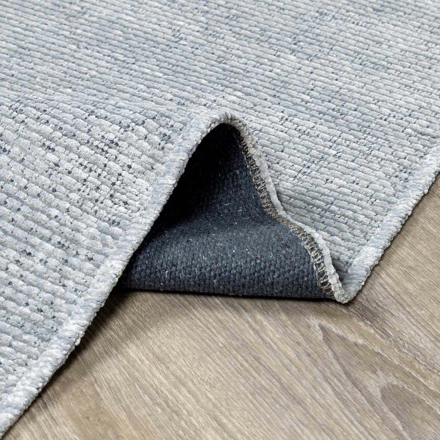Close-up of the Isako Blue & Gray Solid Washable Area Rug showing its texture and backing. Fold