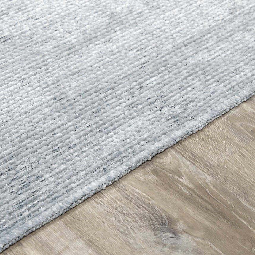 Close-up of the Isako Blue & Gray Solid Washable Area Rug showing texture and color on wood floor. Pile