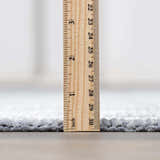 Close-up of the Isako Blue & Gray Washable Area Rug showing its plush pile height with a ruler for scale. Pile