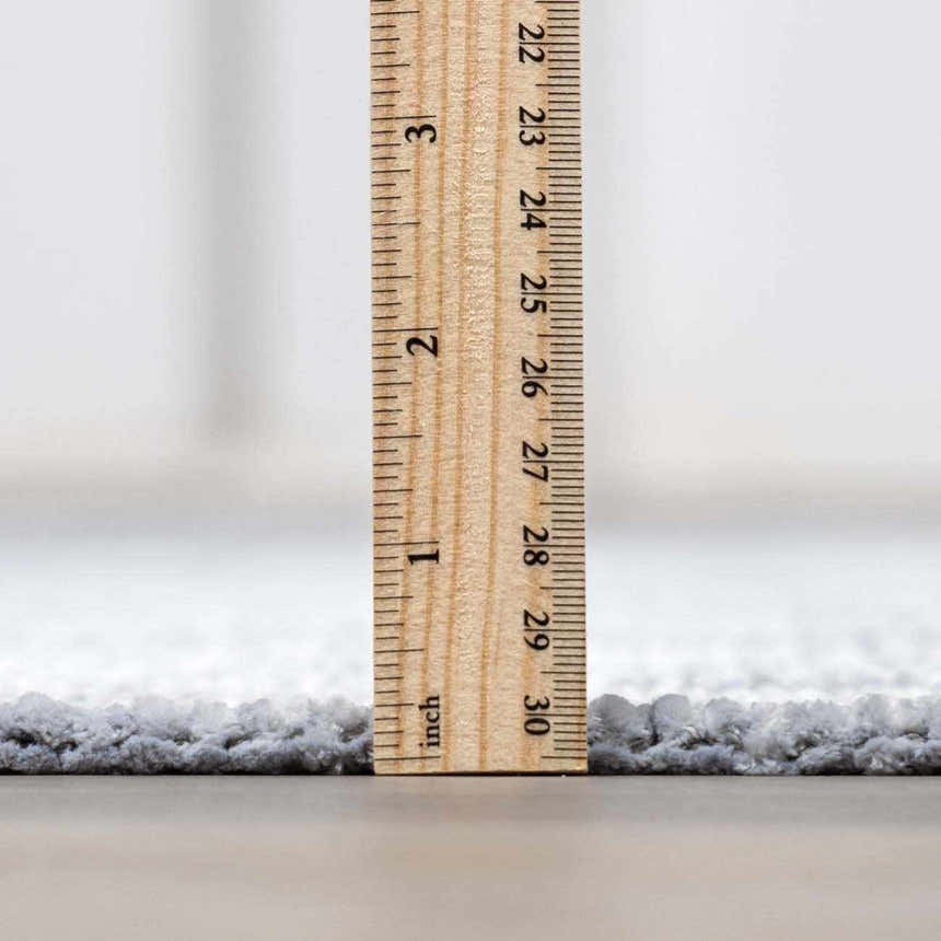 Close-up of the Isako Blue & Gray Washable Area Rug showing its plush pile height with a ruler for scale. Pile