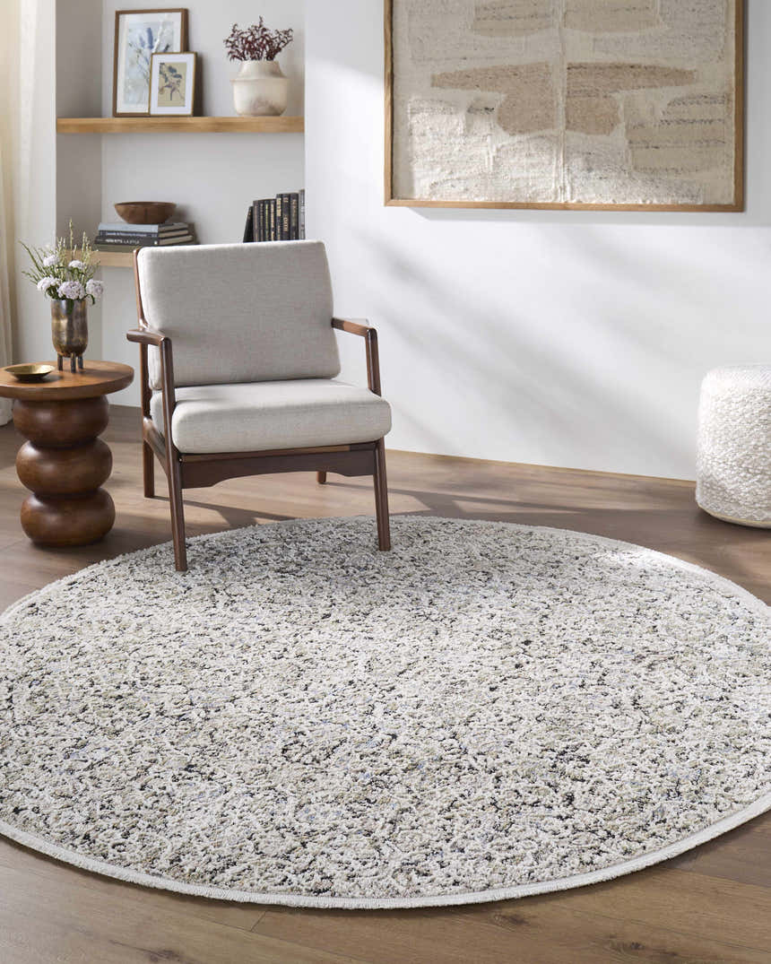 Living room scene with a round Haran Cloud Gray area rug, gray chair, wood side table, and neutral decor. Roomscene-Round