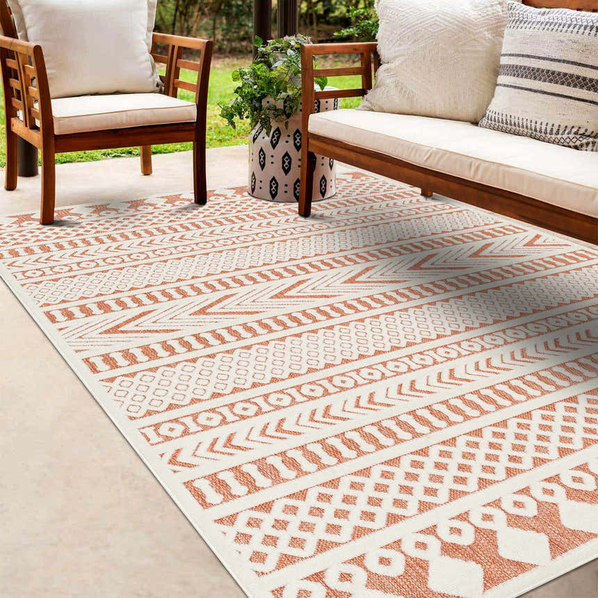 Outdoor patio scene with wooden furniture and a bone and clay colored Jove Orange Outdoor Rug. Roomscene-Rectangle
