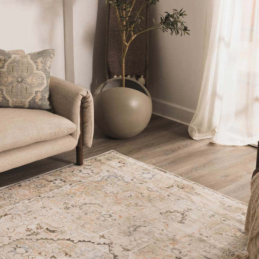 Living room scene with a neutral sofa and Standon Vintage Flat Pile Washable Rug in a faded traditional pattern. Styleshot