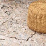 Close-up of Standon Vintage Flat Pile Washable Rug with oriental design in blue, charcoal, and dusty pink. Jute pouf on rug. Styleshot