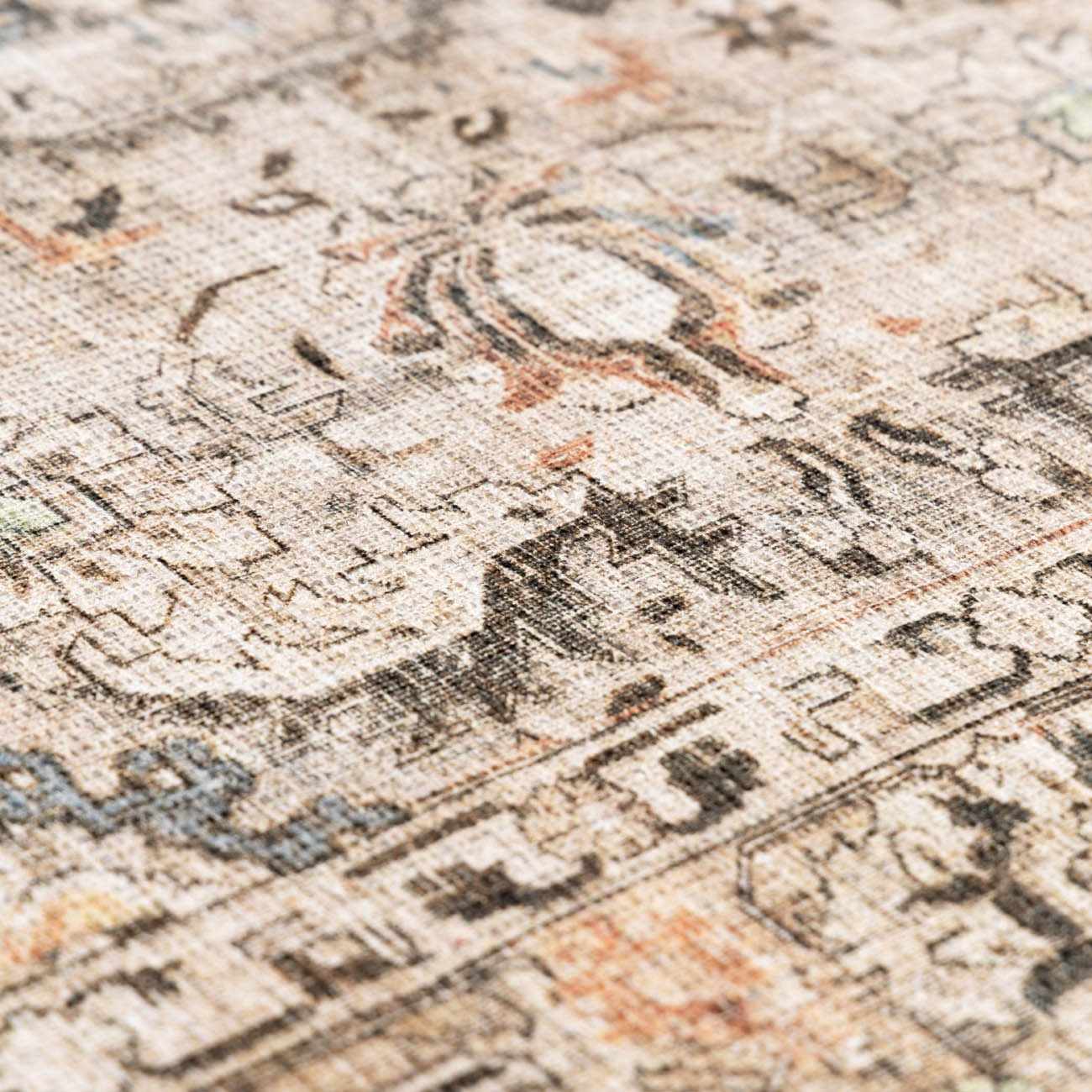 Close-up of the Standon Vintage Flat Pile Washable Rug. Beige rug with charcoal, blue, and terracotta traditional Persian-style pattern. Texture