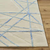 Close-up of the Hiba Area Rug. Hand-tufted wool rug in beige with a modern, geometric slate blue pattern. Soft texture. Front