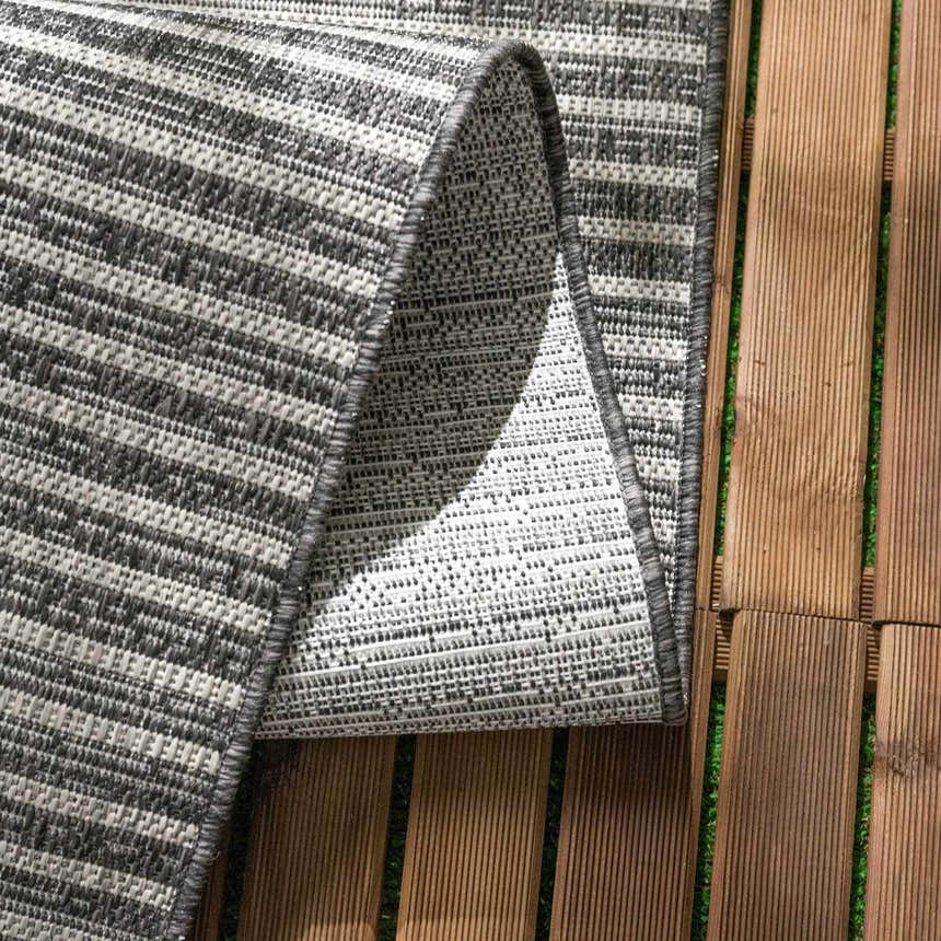 Close up of the Stephan Area Rug showing its gray and cream horizontal stripes and woven texture. Fold