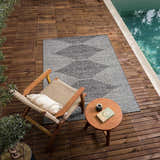 Outdoor scene with Stephan Area Rug in black, charcoal, and cream. Rug is styled by a pool with chair and side table. Roomscene-Rectangle