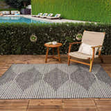 Outdoor patio scene with a gray and cream Stephan Area Rug, wood chair, and pool in the background. Roomscene-Rectangle