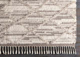 Close-up of the Tankerton Area Rug. Oatmeal and dark brown wool rug with a textured, geometric pattern and fringe. Corner