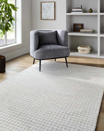 Living room scene with a gray chair on the beige and off-white checkered Anahid Bone Area Rug. Modern style. Roomscene-Rectangle