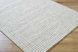 Close up of the Anahid Gray Area Rug. Checkered, hand tufted wool rug in ash, light silver, and off white. Corner