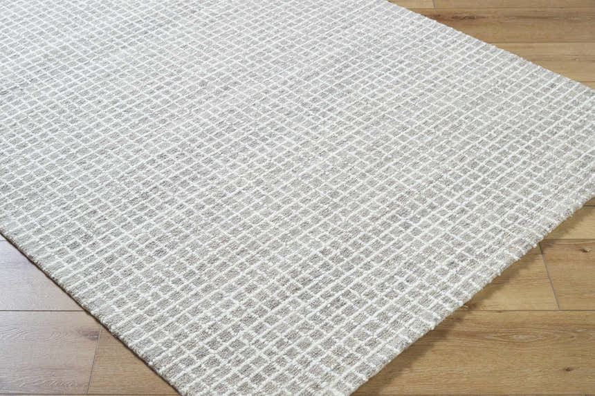 Close up of the Anahid Gray Area Rug. Checkered, hand tufted wool rug in ash, light silver, and off white. Corner