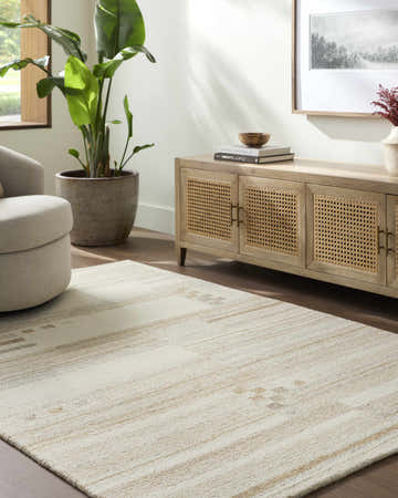 Living room scene with a light silver and sage Tilak Modern Wool Rug, beige armchair, and wooden cabinet. Roomscene-Rectangle