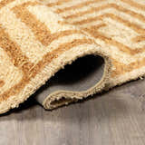 Close-up of the hand-tufted Wasim Area Rug. Camel and pearl geometric pattern, 100% wool texture. Fold