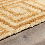 Close up of the hand tufted Wasim Area Rug, featuring a geometric pattern in camel and pearl wool. Pile