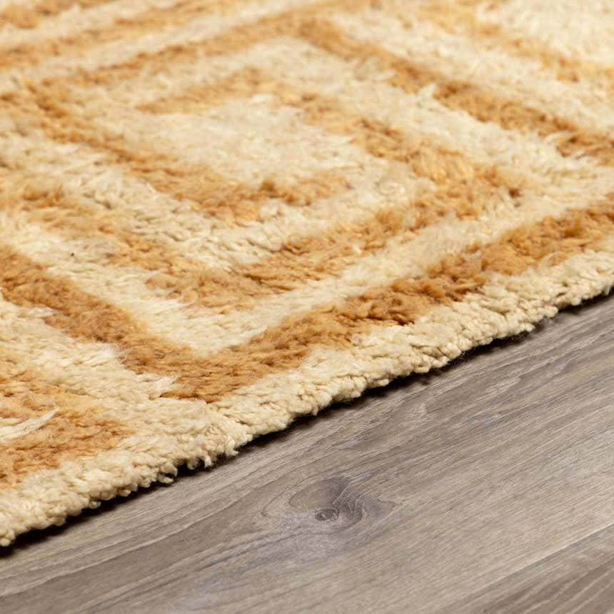 Close up of the hand tufted Wasim Area Rug, featuring a geometric pattern in camel and pearl wool. Pile