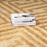 Close-up of the hand-tufted Wasim Area Rug, a wool rug in camel and light wood with a geometric pattern. Styleshot
