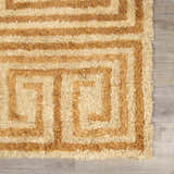 Close-up of the hand-tufted Wasim Area Rug. Wool rug features a geometric, maze-like pattern in tan and light wood tones. Swatch