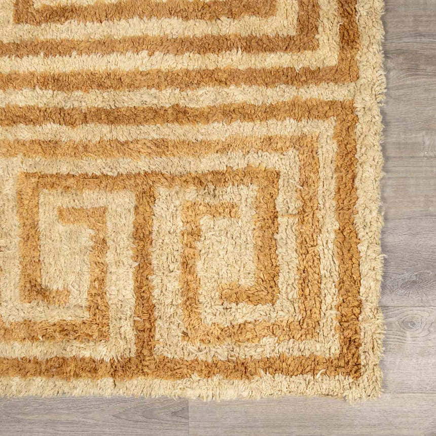 Close-up of the hand-tufted Wasim Area Rug. Wool rug features a geometric, maze-like pattern in tan and light wood tones. Swatch
