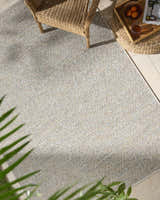 Close-up of Thanh Ivory Area Rug showing woven texture, neutral colors, and subtle pattern in a bright, airy sunroom. Roomscene-Rectangle