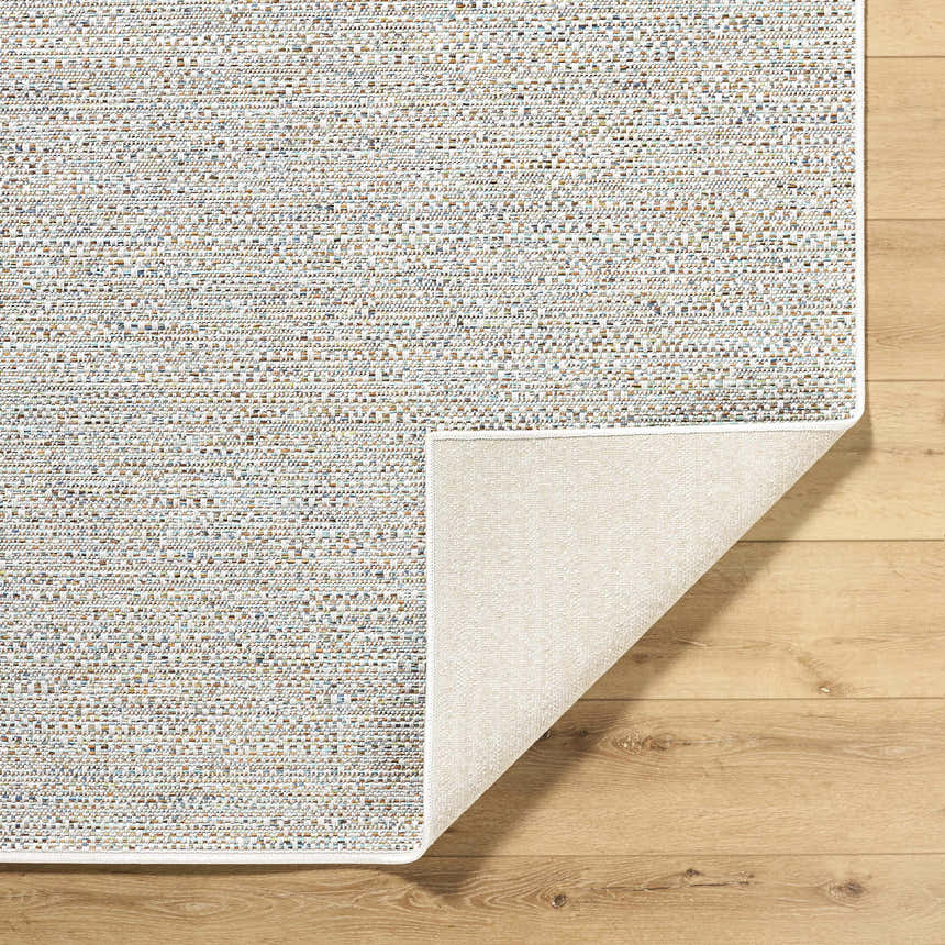 Close-up of Thanh Ivory Area Rug showing woven texture, neutral colors, and rug backing on wood floor. Fold