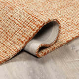 Close-up of the Teresita Area Rug, a hand-tufted wool rug in burnt orange and ivory with a textured, contemporary design. Fold