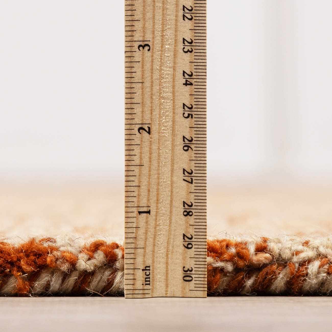 Close-up of Teresita Area Rug showing pile height. Burnt orange and ivory wool texture, hand tufted. Pile