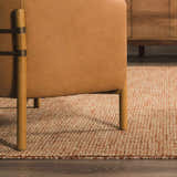 Close-up of Burnt Orange and Ivory Teresita Area Rug under a leather chair in a living room setting. Styleshot