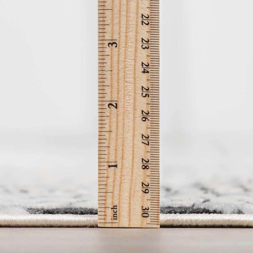 Close-up of the Terlingua Area Rug showing the pile height with a ruler. Beige and black tones. Pile