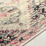 Close-up of the Trudy Area Rug. Farmhouse style rug with pink, black, and blue floral pattern on a cream background. Texture