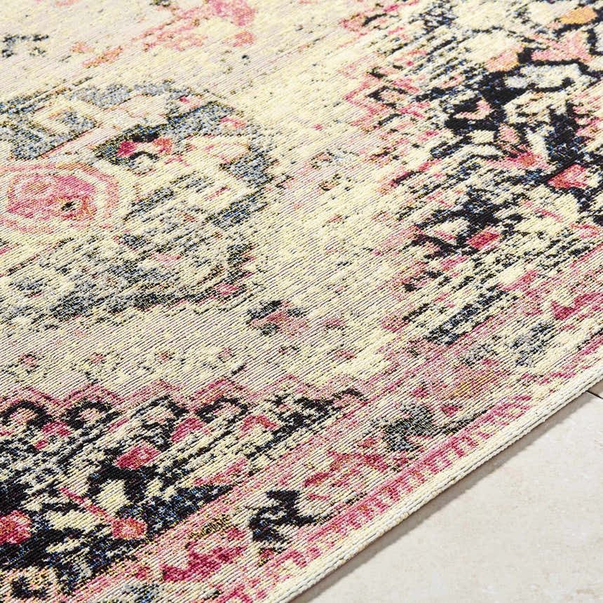 Close-up of the Trudy Area Rug. Farmhouse style rug with pink, black, and blue floral pattern on a cream background. Texture