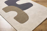 Close-up of the hand-tufted Terah Ivory Area Rug. Features a contemporary design with charcoal and taupe abstract shapes on ivory wool. Corner