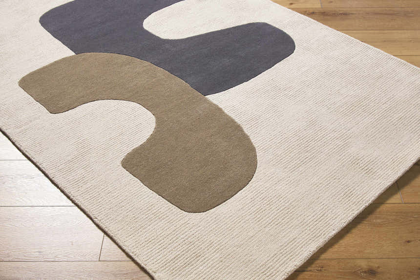 Close-up of the hand-tufted Terah Ivory Area Rug. Features a contemporary design with charcoal and taupe abstract shapes on ivory wool. Corner