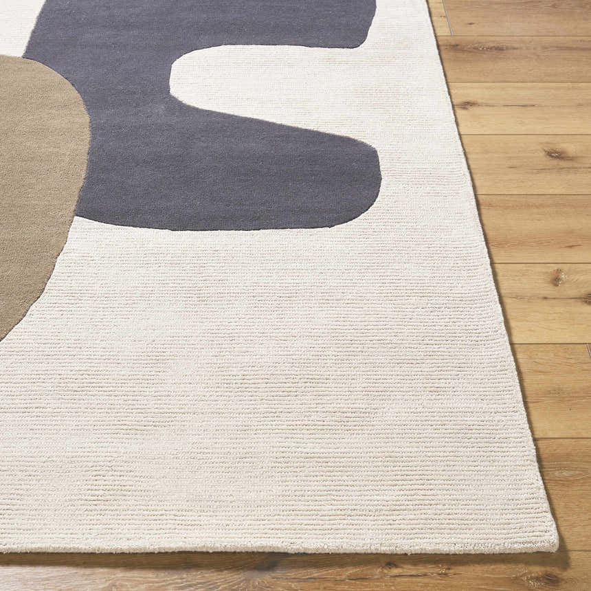Close-up of the hand-tufted Terah Ivory Area Rug. Features charcoal, ivory, and taupe abstract shapes on a wool base. Front