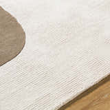 Close up of the Terah Ivory Area Rug showing the ivory wool texture and taupe circle design. Texture