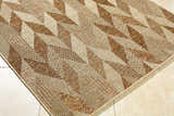 Close-up of the Andrea Burnt Sienna Area Rug. Beige, rust, and terracotta hues create a geometric, woven pattern. Corner