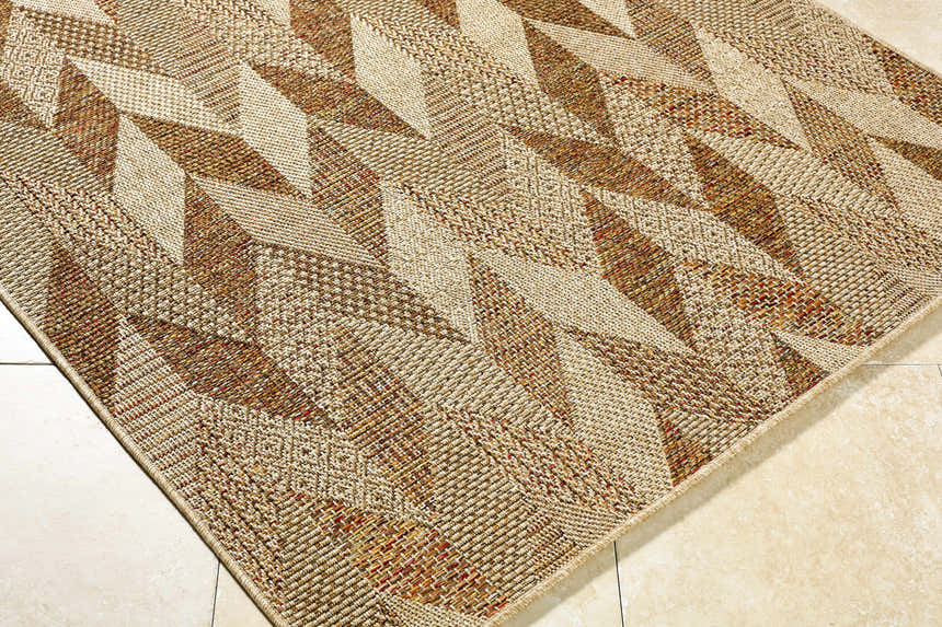 Close-up of the Andrea Burnt Sienna Area Rug. Beige, rust, and terracotta hues create a geometric, woven pattern. Corner