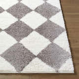 Close-up of Achaia Dark Gray Area Rug with a diamond pattern in gray and ivory on wood flooring. Front