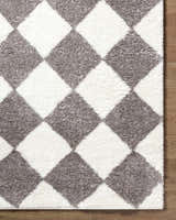 Close-up of the Achaia Dark Gray Area Rug. Diamond pattern in ivory and dark gray shag texture. Corner