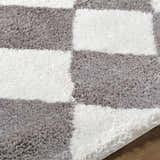 Close-up of the Achaia Dark Gray Area Rug, a shag rug with a gray and ivory checkerboard pattern. Texture
